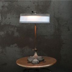 a table lamp sitting on top of a wooden table next to a black wall with a white light