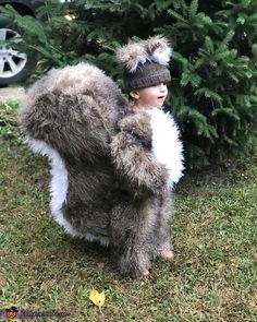 a young boy dressed up as a furry animal with his arms wrapped around the tree