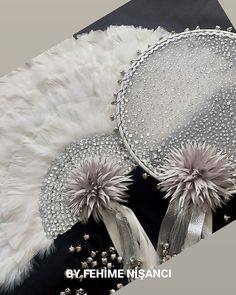 two hats with white fur and silver beads on top of each other, next to a black background