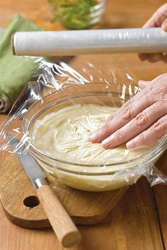 an older person is making food in a bowl on a wooden table with a rolling pin