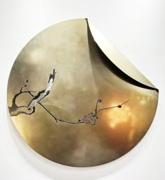 a circular metal object with a bird on it's branch in front of a cloudy sky