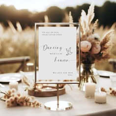 a sign sitting on top of a table next to some candles and vases with flowers