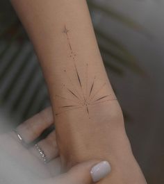 a woman's hand with a small tattoo on her left wrist and the other arm