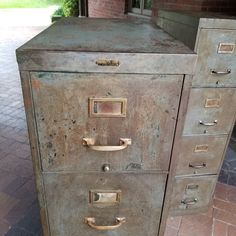 an old metal filing cabinet sitting on top of a brick floor