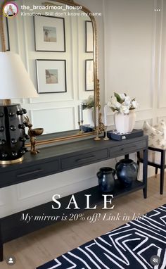 a black and gold console table with a mirror on it, next to a lamp