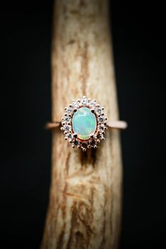 an opal and diamond ring sitting on top of a piece of wood