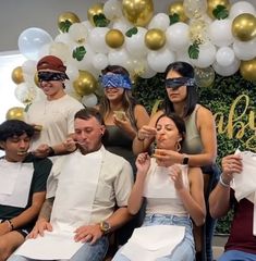 a group of people sitting next to each other in front of a balloon filled wall