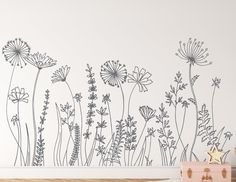 a wall with flowers painted on it next to a wooden table and chest of drawers