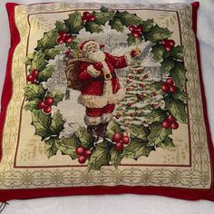 a christmas pillow with a santa clause and holly wreath on the front, holding a bag