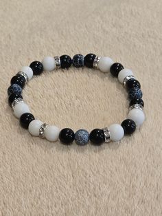 Black, grey and white beaded bracelet. One of a kind with a touch of silver. Elegant Black Beaded Bracelets With Silver Beads, Silver Beaded Bracelets With Black Round Beads, White Stretch Bracelet With Silver Beads, Black And Grey Beaded Bracelet, Elegant White Bracelets With Black Beads, Elegant White Bracelet With Black Beads, Silver Crystal Bracelet With Black Beads, White Stretch Bracelet With Black Beads Gift, Elegant White Stretch Bracelet With Black Beads