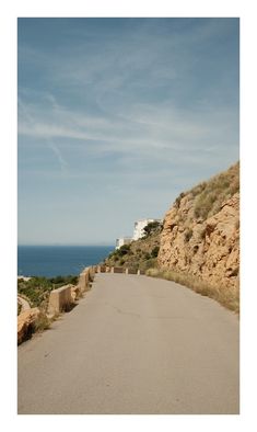 an empty road next to the ocean on a sunny day