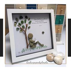 a white frame with some rocks and a tree on the bottom, and another picture behind it