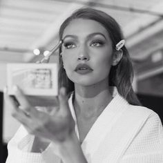 a woman with makeup brushes in her hair and holding up a box that says beauty on the inside