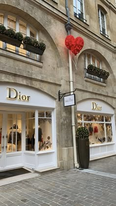 a store front with two red heart balloons in the window and an iron lamp post