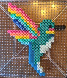 a colorful bird made out of legos on top of a brown surface with white dots