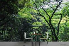 two chairs sitting at a table in front of a forest wall mural