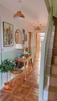 a hallway with wooden flooring and pictures on the wall, along with a plant