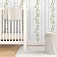 a white crib in front of a blue and white wallpaper