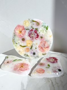 three plates with flowers painted on them sitting on a marble countertop next to each other