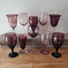 a group of wine glasses sitting on top of a wooden table next to each other