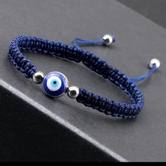 the evil eye bracelet is made with blue seed beads and silver bead ends, on a black surface