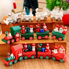 a group of toy trains sitting on top of a wooden table next to a christmas tree