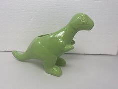 a green toy dinosaur sitting on its hind legs