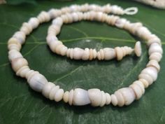 This is a very unique and vibrant piece made with Hawaiian white cone shells with puka shells collected from the beaches of Kauai, Hawaii. Puka shells are actually the tops of cone shells that have been tumbled in the ocean waves for many years. These leis are much more lightweight then a lei made with just puka shells. This necklace looks great on men and women. It is strung with 80lb' test braided nylon line, so it is very strong and can be worn in fresh or salt water. There are less Cone an P Traditional Adjustable Shell Necklace, Adjustable Artisan Shell Necklace, Handmade Spiritual Shell, Ocean-inspired Shell With Round Beads, Ocean-inspired Shell Beads, Handmade Natural Shell Necklace, White Shell Necklace With Natural Stones, Artisan White Shell Necklace For The Beach, Artisan Beaded Shell Necklace