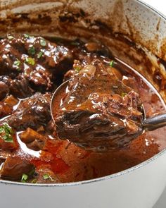 a pot full of stew with a ladle scooping some food out of it