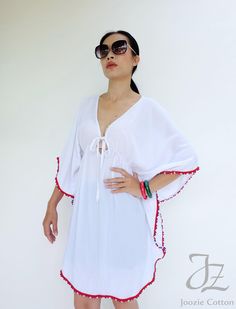 "🚚..ALL ORDERS ARE SHIPPED VIA DHL EXPRESS MAIL Opt for the perfect beach cover up with this white kaftan cut with kaftan sleeves, v-neck with drawstring tie closure and pom pom trim along edges. Layer it over your brightly color bikinis for a beach ready look. It's an irresistibly stylish choice for sun-soaked getaways. DETAILS: * Pull-on style * V-neck with drawstring tie closure * Kaftan sleeve. * Red, white and blue pom pom trim along edges * Ruched waistline detail at center front and cent Beachwear V-neck Cover-up With Tassels, Bohemian Cover-up With Back Tassel Tie-up, Vacation V-neck Kaftan With Tassel Ties, White V-neck Bohemian Kimono, White V-neck Kimono For Festival, White V-neck Summer Kimono, Bohemian White V-neck Cover-up, Summer V-neck Kaftan For Resort, Summer V-neck Tunic For Festivals