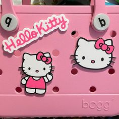 a pink hello kitty purse with two stickers on it