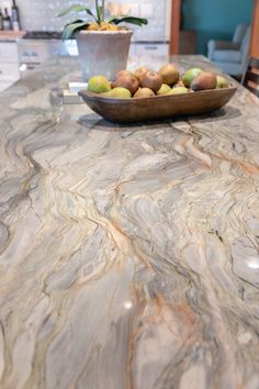 a bowl full of fruit sitting on top of a marble countertop in a kitchen