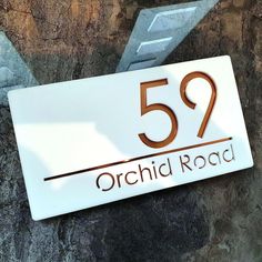 a sign that is on the side of a stone wall saying 55 orchid road in front of it