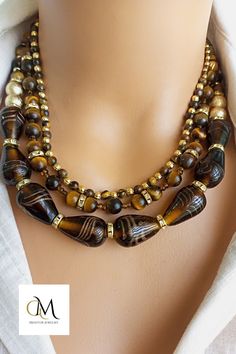 This exquisite piece perfectly combines vibrant Indian glass beads with the earthy allure of Tiger Eye natural stones. Each bead is meticulously handcrafted, showcasing the rich cultural heritage of India. The warm hues of the Tiger Eye stones create a captivating contrast against the intricately designed glass beads, making this necklace a true statement piece. With its adjustable length and secure clasp, it can be easily customized to fit any neckline. Oval Glass Gemstone Beads Jewelry, Brown Multi-strand Jewelry With Colorful Beads, Bohemian Amber Glass Jewelry, Handmade Brown Czech Glass Beads, Bohemian Brown Czech Glass Beaded Necklaces, Bohemian Brown Beaded Necklace With Czech Glass, Bohemian Brown Czech Glass Beaded Necklace, Brown Glass Beads For Jewelry Making, Unique Brown Jewelry With Polished Beads