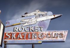 an old neon sign for a skating club with a rocket on top and a skateboard attached to it