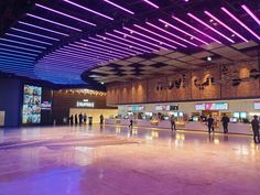 people are standing in the middle of an indoor shopping mall with purple lighting on the ceiling