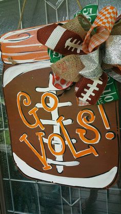 a football ornament hanging on the side of a building with an orange and white bow