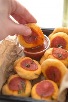 a person dipping some kind of pizza into a bowl