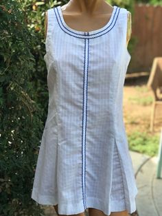 Here is a vintage 1970s white poly cotton tennis dress.Made by June Marks Tennis Fashions. Size 10.Following  are the measurements. Bust 34" waist 32",Hips full with pleats,Length 30".Zips up the back.Small square print on the solid white fabric.Pleats on front and Le back.Blue trim.In nice vintage condition.Please take special consideration of measurements. 1970s sizing was very small to today's standards. Tennis dresses were very short not like a regular dress. So please take special note of length. If you live overseas please email me first before purchasing for mailing cost. Price quoted is for USA only Sleeveless Cotton Tennis Dress For Summer, White Cotton Tennis Dress For Summer, White Sleeveless Dress With French Seams, Classic Fitted Tennis Dress For Spring, White Summer Dress With Pintucks, Summer White Dress With Pintucks, Fitted Cotton Dress With Pintucks, Classic Fitted Summer Tennis Dress, Classic Fitted Tennis Dress For Summer