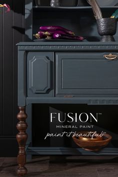 a wooden cabinet sitting next to a vase on top of a table with a sign that says, fuson mineral paint part of beautiful