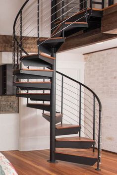 there is a spiral staircase in the living room with wood flooring and white walls