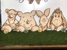 three winnie the pooh cut outs are on display in front of a large sign