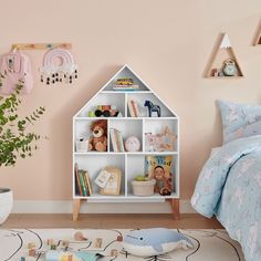 a child's bedroom with pink walls and white shelving unit filled with toys