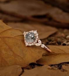 an engagement ring on top of a leaf in the woods, with diamonds surrounding it