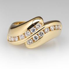 This Stephen Vincent designed ring features a curved bypass design and is accented with fourteen (14) round brilliant cut diamonds set into two channels. The ring measures 13.0mm at the top, rises 5.0mm above the finger, tapering to 4.2mm wide and 1.3mm thick at the base of the shank. Trademarks: S.VINCENT. It is currently a size 8.5. One of the diamonds is unnoticeably chipped. Luxury Brilliant Cut Bypass Ring For Formal Occasions, Luxury Bypass Ring With Brilliant Cut For Formal Occasions, Luxury Bypass Ring With Brilliant Cut For Formal Events, Luxury Bypass Ring With Polished Finish, Timeless Diamond Bypass Ring For Formal Occasions, Elegant Bypass Ring With Tension Setting For Formal Occasions, Elegant Polished Bypass Ring For Anniversary, Luxury Bypass Ring With Vvs Clarity Round Cut, Luxury Vvs Clarity Round Cut Bypass Ring