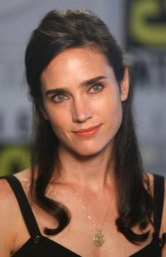 a close up of a person wearing a black dress and smiling at the camera with a star wars logo in the background