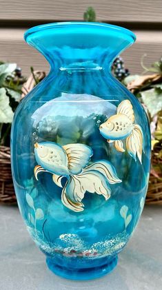 a blue glass vase with gold fish painted on it