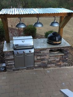 an outdoor bbq grill with three lights on it's sides and a table in the background