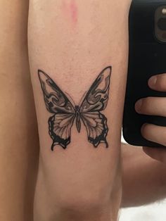 a woman's leg with a butterfly tattoo on it and a phone in the other hand