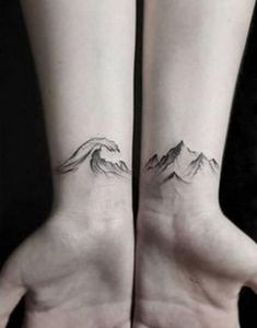 two hands with mountains tattoo on them